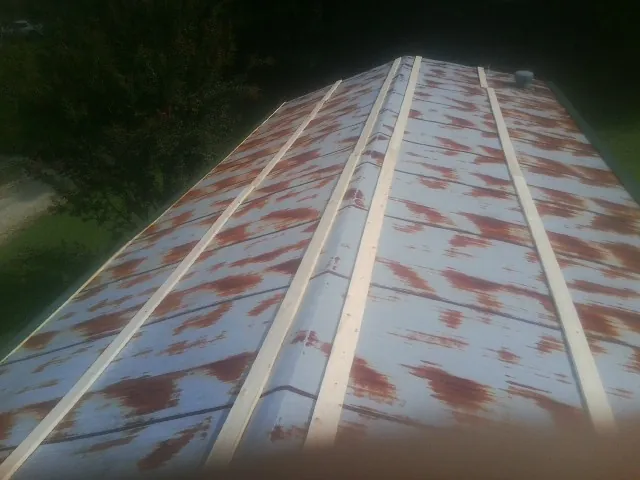 Rusted metal roof panels with new wood purlins before replacement — Storm Damage Roof Repair in Hollis by Roofing Brothers
